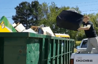 Man Throws Items in Dumpster